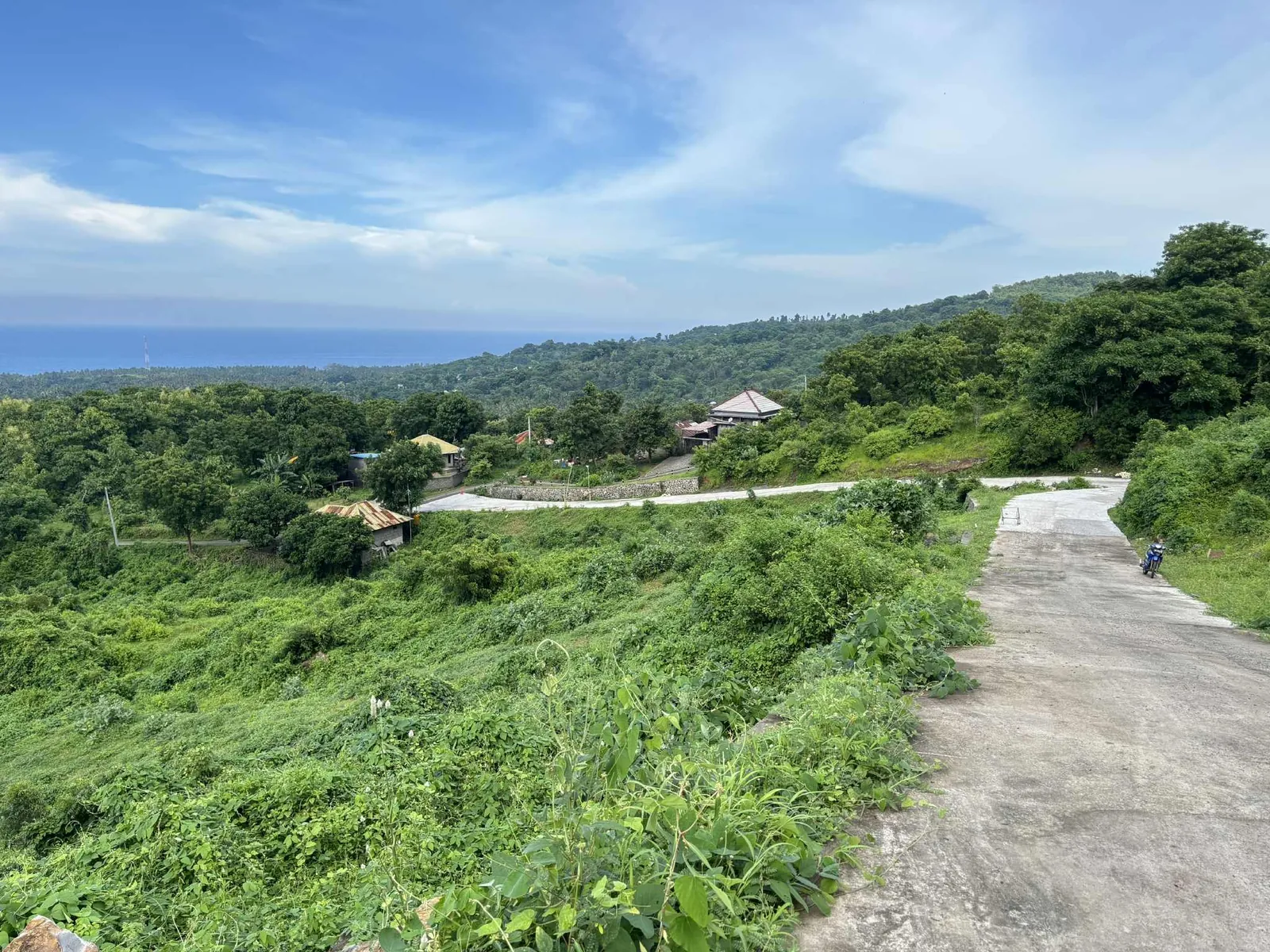 The access road curving through green slopes, with the sea beyond